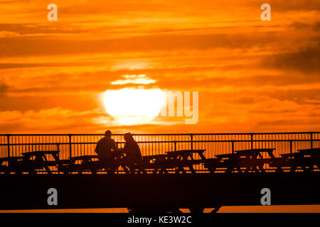 Aberystwyth Galles Regno Unito, mercoledì 18 ottobre 2017 Regno Unito Meteo: in un periodo di calma tra Storm Ophelia e l'imminente Storm Brian (previsto per sabato), le persone si godono gli ultimi momenti del tramonto sul Royal Pier di Aberystwyth, sulla costa di Cardigan Bay nel galles occidentale. foto: Keith Morris/Alamy Live News Foto Stock