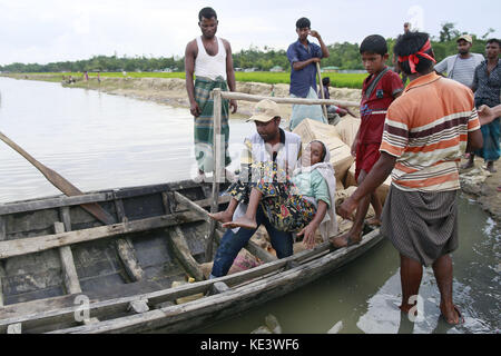 Ukhiya, Bangladesh. Xviii oct, 2017. Un uomo del Bangladesh porta un rohingya donna musulmana rajamma, che hanno attraversato dal Myanmar in Bangladesh, verso una barca riempita con gli aiuti alimentari per i rifugiati a trefoli in anjuman para, Bangladesh, 18 ottobre 2017. migliaia di rohingya musulmani che hanno attraversato la frontiera per prima questa settimana sono camping in assenza o con un po' di cibo e assenza di servizi igienici, trascorrere giorni e notti in campi aperti solo con fogli di plastica come rifugi vicino al punto zero del Bangladesh-myanmar confine. Credito: suvra kanti das/zuma filo/alamy live news Foto Stock