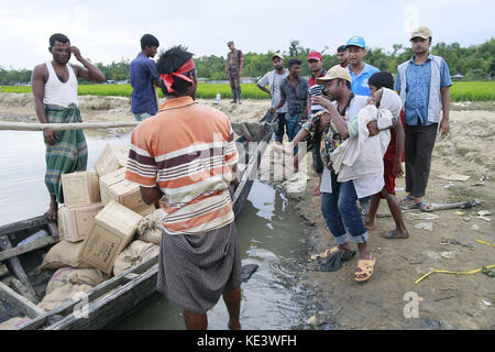 Ukhiya, Bangladesh. Xviii oct, 2017. Un uomo del Bangladesh porta un rohingya donna musulmana rajamma, che hanno attraversato dal Myanmar in Bangladesh, verso una barca riempita con gli aiuti alimentari per i rifugiati a trefoli in anjuman para, Bangladesh, 18 ottobre 2017. migliaia di rohingya musulmani che hanno attraversato la frontiera per prima questa settimana sono camping in assenza o con un po' di cibo e assenza di servizi igienici, trascorrere giorni e notti in campi aperti solo con fogli di plastica come rifugi vicino al punto zero del Bangladesh-myanmar confine. Credito: suvra kanti das/zuma filo/alamy live news Foto Stock