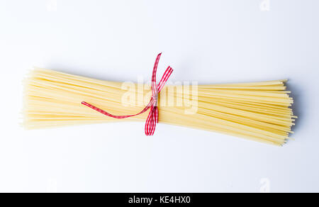 Non cotti spaghetti legato con una corda isolato su bianco Foto Stock