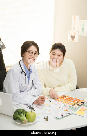Ritratto di medico sorridente e giovane donna grassa a obesità clinica Foto Stock