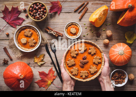 In casa torta di zucca per cena di ringraziamento tabella. mani tutta la torta di zucca. tavola in legno rustico sfondo. vista superiore Foto Stock