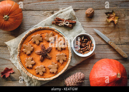 Torta di zucca autunnale con noci pecan e biscotti alle spezie di pan di zenzero su un tavolo di legno. Vista dal piano d'esame Foto Stock
