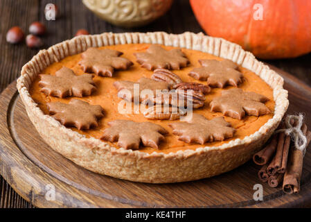 Tutta la torta di zucca con noci pecan e gingerbread cookie sul pannello di legno. primo piano Foto Stock