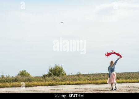 Elegante donna slanciata, agitando la mano aeromobile che vola in estate giornata soleggiata. Viaggi, vacanze, concetto di avventure. Foto Stock