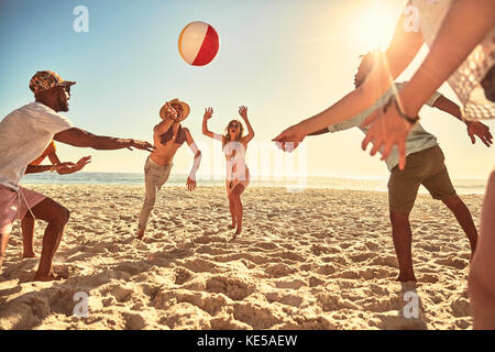 Giocosi giovani amici che giocano con la palla da spiaggia in estate soleggiata spiaggia Foto Stock