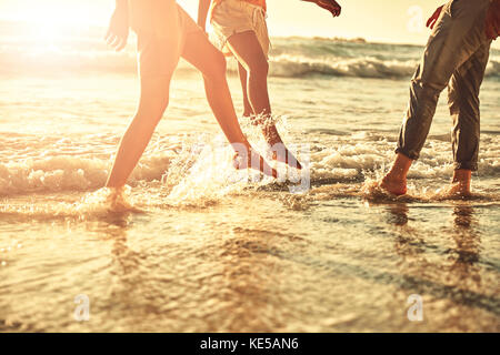 I giovani amici si tuffano nel surf estivo soleggiato dell'oceano Foto Stock