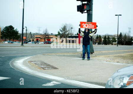 Un uomo che tiene in braccio Papa Murphy firma una giornata fredda che pubblicizza 10 dollari per ogni pizza grande sperando che ci fermiamo qui. Maple Grove, Minnesota, Minnesota, Stati Uniti Foto Stock