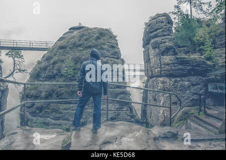 Lonely triste un uomo non identificato sorge sotto la pioggia e nebbia sulla cima di una scogliera. Possibile tentativo di suicidio. Il telaio orizzontale. Foto Stock