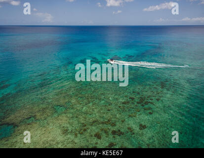 Un acqua sciatore passa al di sopra di una barriera corallina di mullins beach sull'isola caraibica di Barbados. Foto Stock