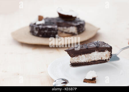 Una bella materie vegan bounty torta decorata in un esotico forma su di un tavolo di legno. Foto Stock