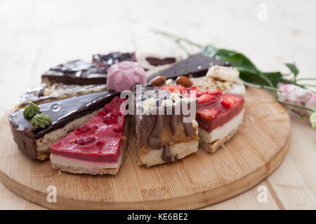 Diversi tipi di materie vegan torte su un piatto di legno in un po' di pasta frolla. Foto Stock