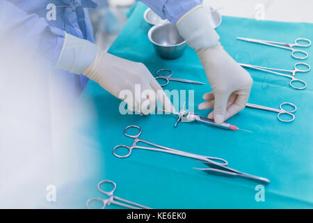 Chirurgo in guanti di gomma preparazione di strumenti chirurgici su vassoio Foto Stock