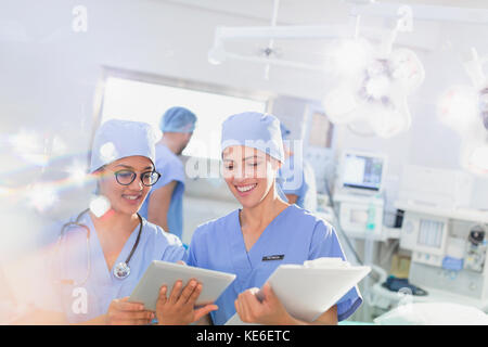 Sorridente chirurghi che utilizzano tablet e appunti digitali durante il funzionamento camera Foto Stock