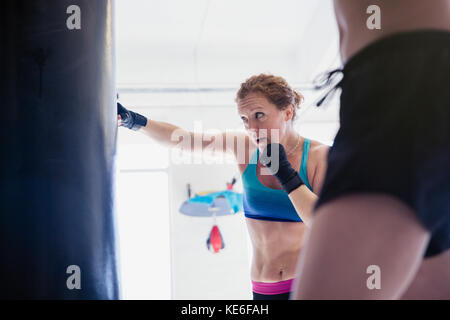 Pugilato femminile determinato e duro a sacchetto di punzonatura in palestra Foto Stock