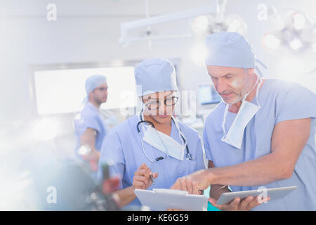 Chirurghi con tablet digitale che parlano di documenti sulla clipboard in funzione camera Foto Stock