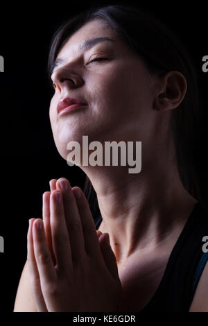 Felice fedeli donna orante e sorridente nella felicità, Bliss e pace, sensazione di ispirazione con la presenza di Dio e della sua grazia. Foto Stock