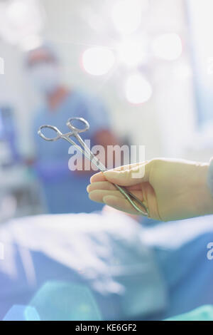 Il chirurgo indossa un guanto in gomma che tiene le forbici chirurgiche in sala operatoria Foto Stock