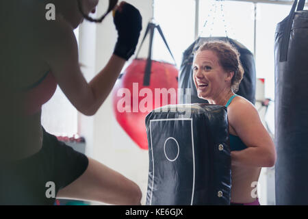 Sorridente pugili femmina kickboxing con imbottitura in palestra Foto Stock