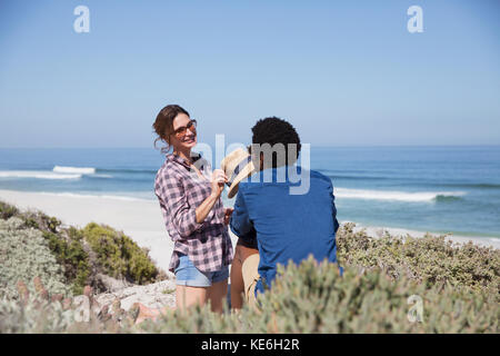 Sorridente coppia multietnica che parla sulla soleggiata spiaggia estiva Foto Stock