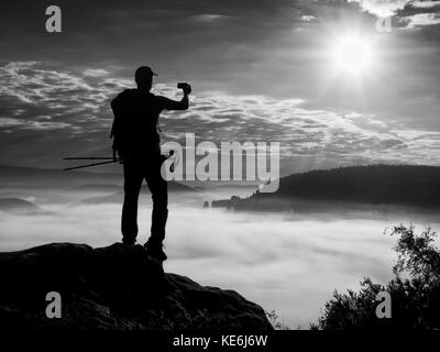Uomo forte escursionista photogrphy con smart phone al picco di montagna. splendida alba. Foto Stock