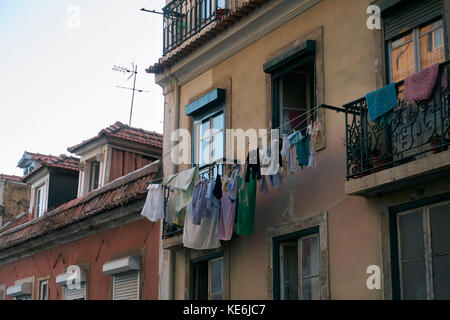 Vestiti appesi ad asciugare in una facciata di edificio a Lisbona, Portogallo Foto Stock