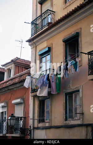 Vestiti appesi ad asciugare in una facciata di edificio a Lisbona, Portogallo Foto Stock