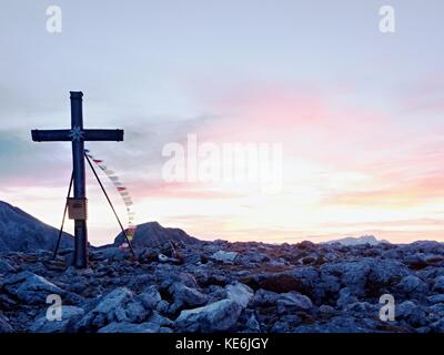 Grande croce sulla cima della montagna come tipico delle Alpi. croce di legno al picco di montagna con la preghiera buddista flags flutter in forte vento. Monumento a vi Foto Stock