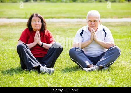 Foto di anziani coppia senior meditando in posizione di parcheggio Foto Stock