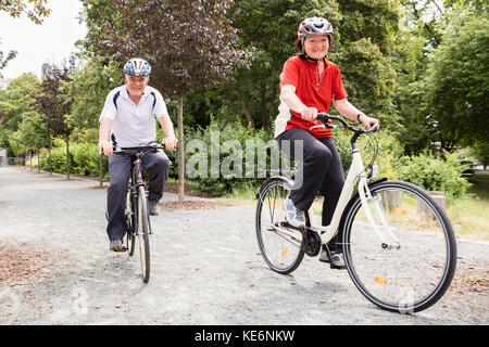 Sorridente anziani coppia Senior in bicicletta nel parco al mattino Foto Stock