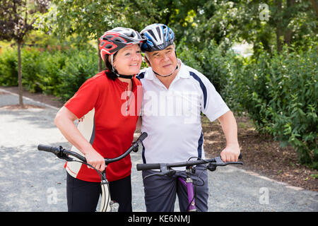 Ritratto di felice coppia di anziani con le loro biciclette Foto Stock