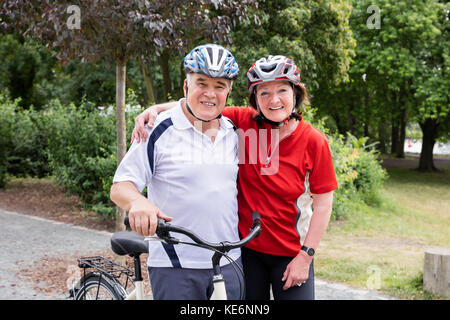 Ritratto di sorridente Coppia senior con noleggio biciclette in piedi insieme in posizione di parcheggio Foto Stock