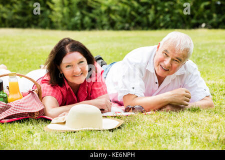 Sorridente coppia Senior giacente su erba nel parco Foto Stock