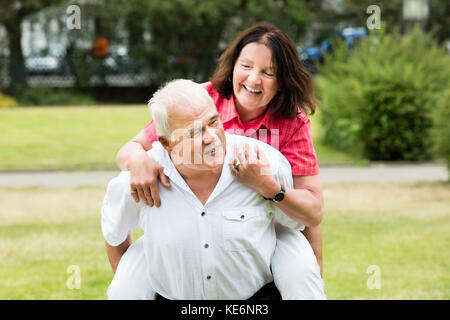 Ritratto di un felice uomo Senior Piggybacking sua moglie Foto Stock