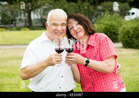 Close-up di sorridere Senior giovane azienda bicchiere di vino Foto Stock