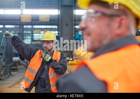 Uomo della casa che usa walkie-talkie in fabbrica Foto Stock