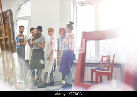 Studenti d'arte e istruttori che discutono di pittura in studio di classe d'arte Foto Stock