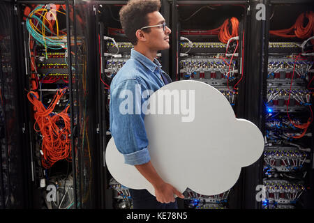 Tecnico IT maschile che trasporta il cloud nella sala server, nel cloud computing Foto Stock