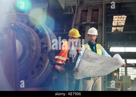 Gli ingegneri riesaminano i progetti nella fabbrica di acciaio Foto Stock