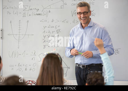 Sorridente insegnante di scienze maschili che conduce la lezione alla lavagna in classe Foto Stock