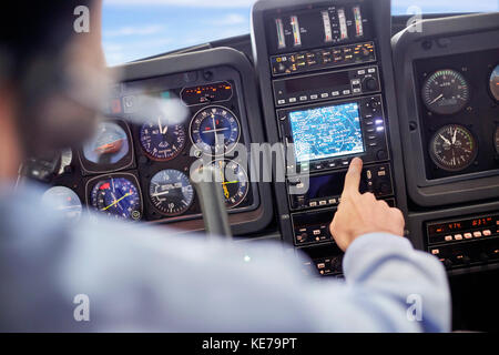 Pilota maschile che utilizza strumenti di navigazione nell'abitacolo dell'aereo Foto Stock