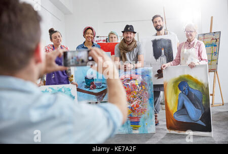 Uomo che fotografa compagni di classe d'arte in studio d'arte Foto Stock