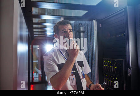 Guardia di sicurezza maschile che utilizza walkie-talkie in una stanza server buia Foto Stock