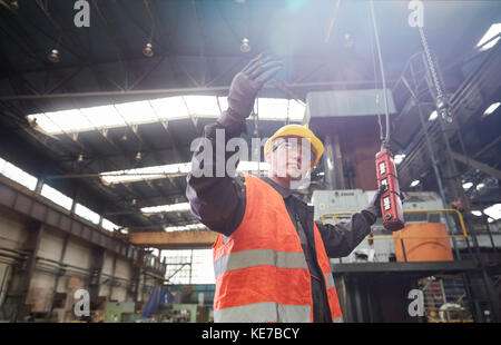 Lavoratore maschile che utilizza macchinari al pannello di controllo, gesturing Foto Stock