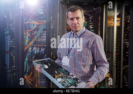 Ritratto tecnico IT di sesso maschile che tiene il pannello nella sala server Foto Stock