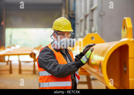 Uomo che indossa una maschera protettiva in fabbrica Foto Stock