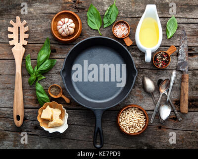 Gli ingredienti in casa il pesto basilico e parmigiano ,l'aglio, olio d'oliva , il dado di pino ,Peppe e sale himalayano sul malandato backgrou in legno Foto Stock
