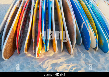 Una pila di coloratissimi longboard tavole da surf posto sulla spiaggia di Waikiki di Oahu, Hawaii, Stati Uniti d'America Foto Stock