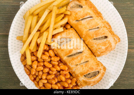 Rotoli di salsiccia con fagioli e patatine fritte contro un verde sullo sfondo di legno Foto Stock