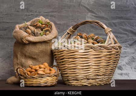 Mandorle su un rustico di legno. Rustica sacco e cestello. schiaccianoci e olio di mandorla. di farina di mandorle. Foto Stock
